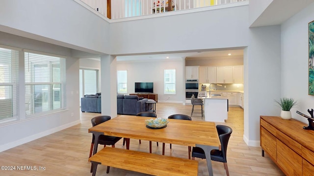 dining room with a towering ceiling and light hardwood / wood-style floors