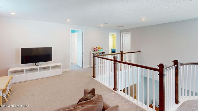 hall with light colored carpet and a textured ceiling