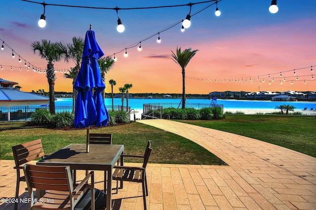 patio terrace at dusk with a yard and a water view