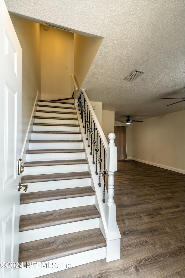 staircase with hardwood / wood-style flooring, ceiling fan, and a textured ceiling