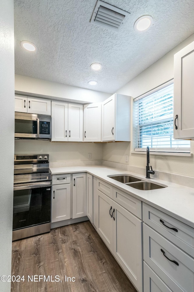 kitchen featuring dark wood-type flooring, sink, white cabinets, and stainless steel appliances