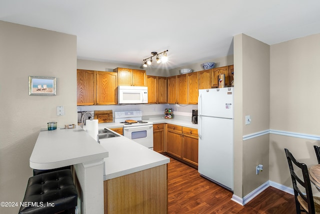 kitchen with dark hardwood / wood-style floors, white appliances, sink, and kitchen peninsula