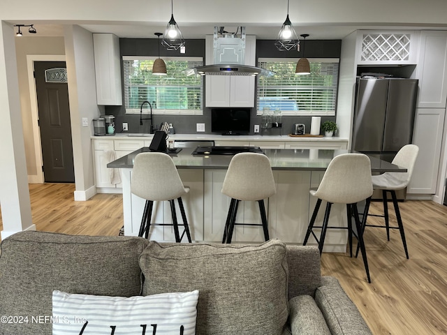 kitchen featuring a kitchen breakfast bar, a healthy amount of sunlight, white cabinetry, and hanging light fixtures