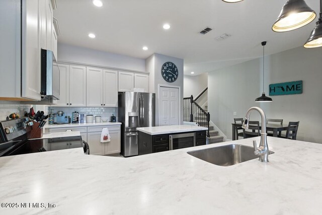 kitchen with white cabinets, a kitchen island, decorative light fixtures, and appliances with stainless steel finishes