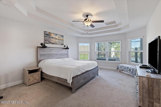 bedroom with ceiling fan, a raised ceiling, and light carpet