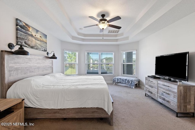 carpeted bedroom with ceiling fan and a raised ceiling