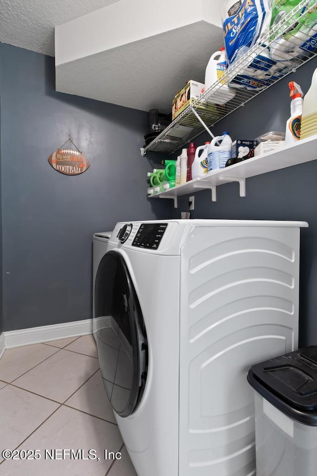 laundry area with tile patterned flooring, washer and dryer, and a textured ceiling