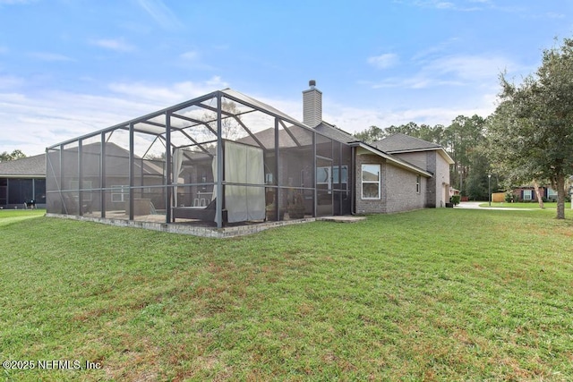 rear view of house with a lawn and glass enclosure