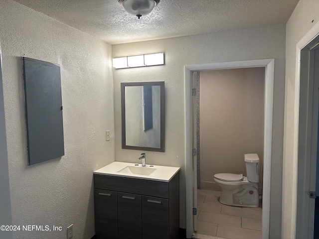 bathroom featuring tile patterned floors, vanity, a textured ceiling, and toilet