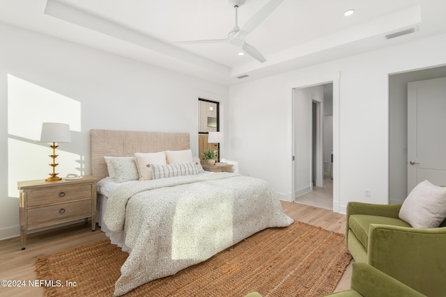 bedroom featuring a raised ceiling, ceiling fan, and wood-type flooring