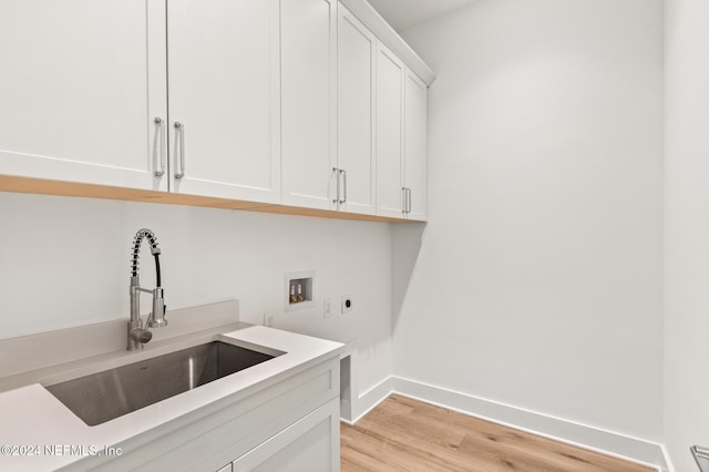 washroom with sink, washer hookup, cabinets, hookup for an electric dryer, and light hardwood / wood-style flooring