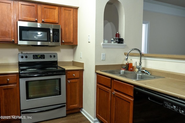 kitchen with crown molding, dark hardwood / wood-style flooring, sink, and stainless steel appliances