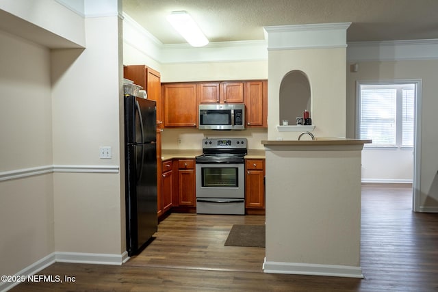 kitchen with sink, ornamental molding, appliances with stainless steel finishes, dark hardwood / wood-style flooring, and kitchen peninsula