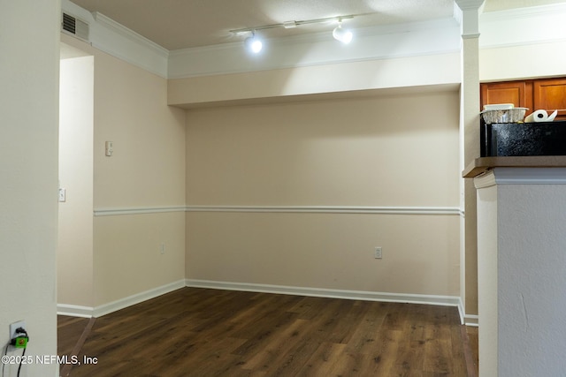 basement with crown molding, rail lighting, and dark hardwood / wood-style floors