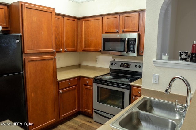 kitchen with sink, appliances with stainless steel finishes, and light hardwood / wood-style flooring