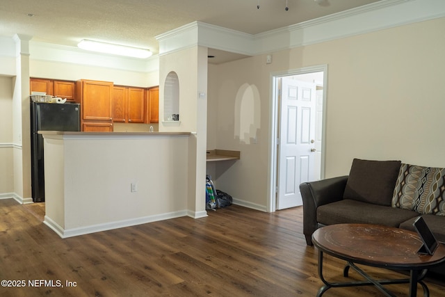 kitchen featuring dark hardwood / wood-style floors, black refrigerator, kitchen peninsula, and crown molding