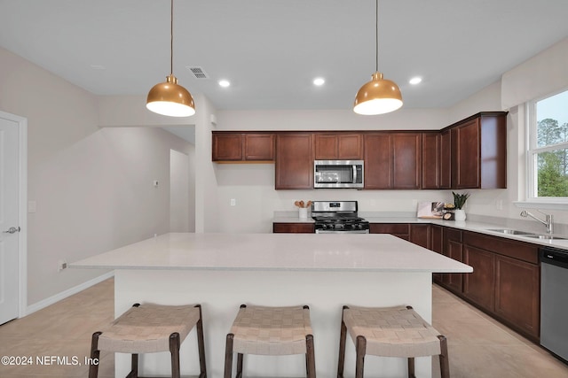 kitchen with appliances with stainless steel finishes, a kitchen island, hanging light fixtures, and sink