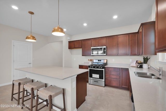 kitchen with sink, a center island, decorative light fixtures, a kitchen bar, and appliances with stainless steel finishes