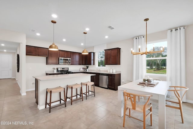 kitchen featuring decorative light fixtures, a kitchen island, a healthy amount of sunlight, and appliances with stainless steel finishes