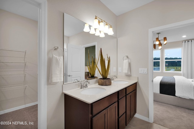 bathroom with tile patterned flooring, a notable chandelier, and vanity