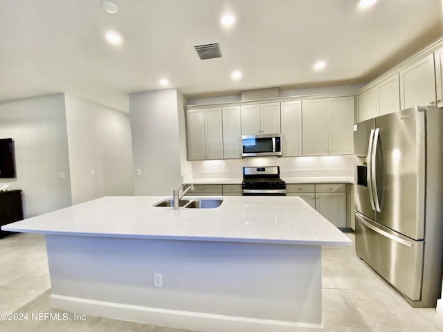 kitchen with appliances with stainless steel finishes, an island with sink, light stone counters, and sink