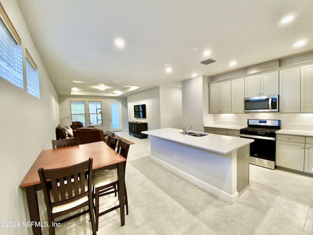 kitchen with gray cabinets, sink, an island with sink, and stainless steel appliances