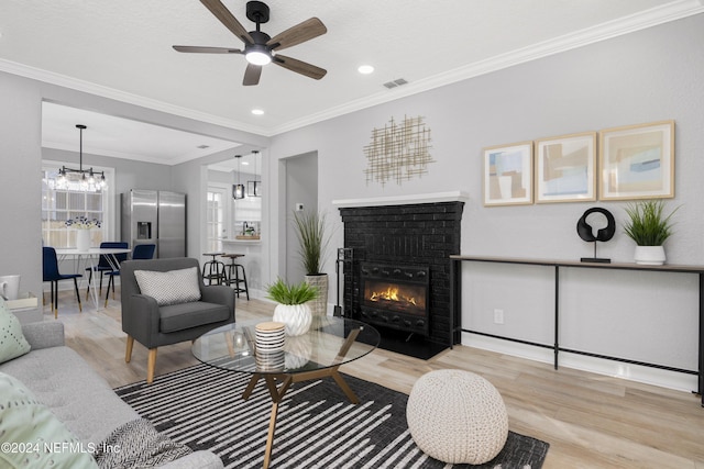 living room featuring light wood-type flooring, ornamental molding, and a brick fireplace