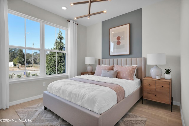 bedroom with a notable chandelier and light wood-type flooring