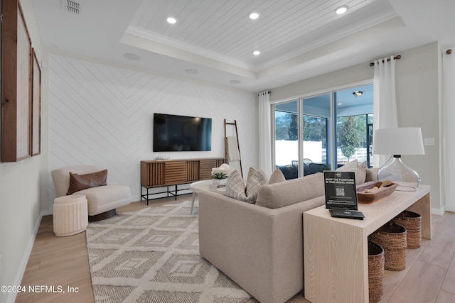 living room with light wood-type flooring, a raised ceiling, and wood walls