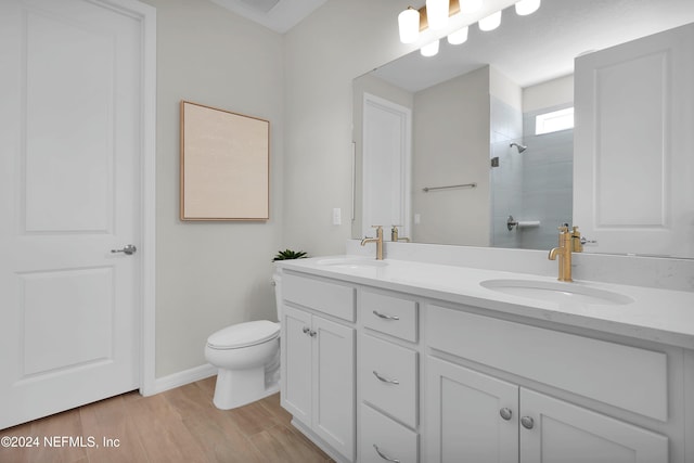 bathroom with hardwood / wood-style flooring, vanity, toilet, and tiled shower