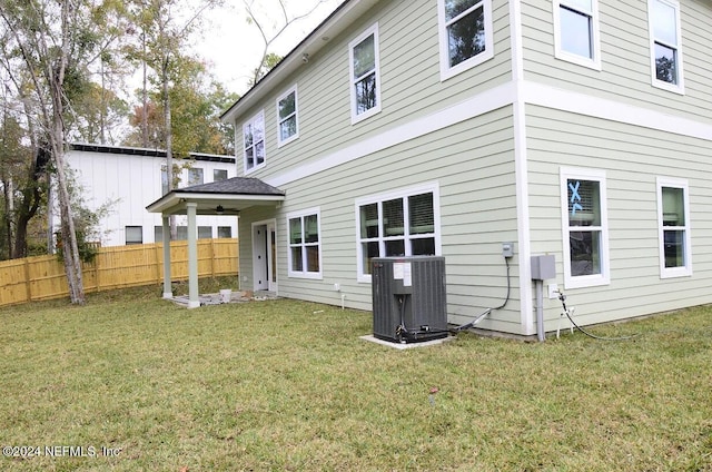 back of house featuring cooling unit and a lawn