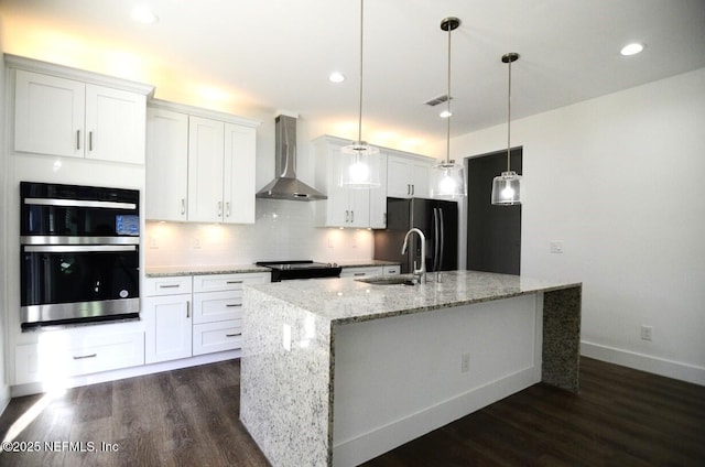 kitchen featuring wall chimney exhaust hood, white cabinets, and pendant lighting