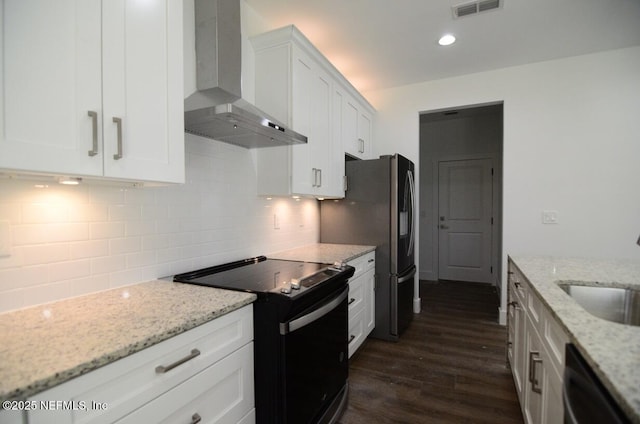 kitchen featuring black appliances, sink, white cabinetry, light stone countertops, and wall chimney exhaust hood