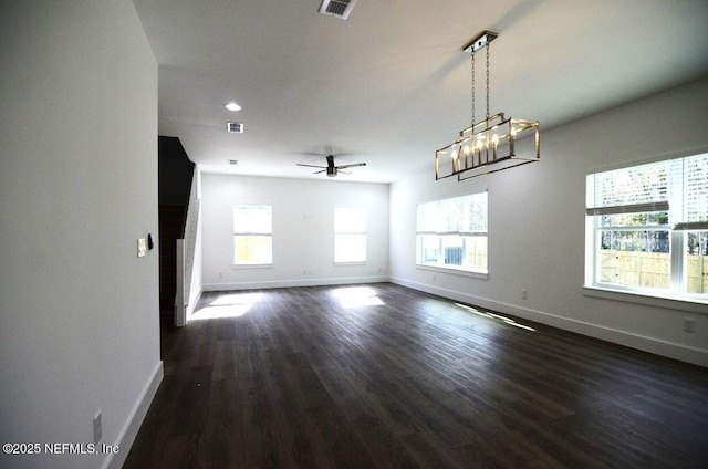 unfurnished living room featuring dark hardwood / wood-style flooring and ceiling fan with notable chandelier