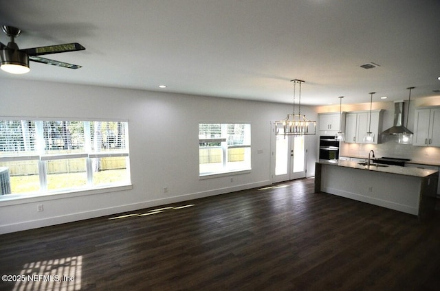 kitchen featuring pendant lighting, white cabinetry, wall chimney range hood, sink, and dark hardwood / wood-style floors