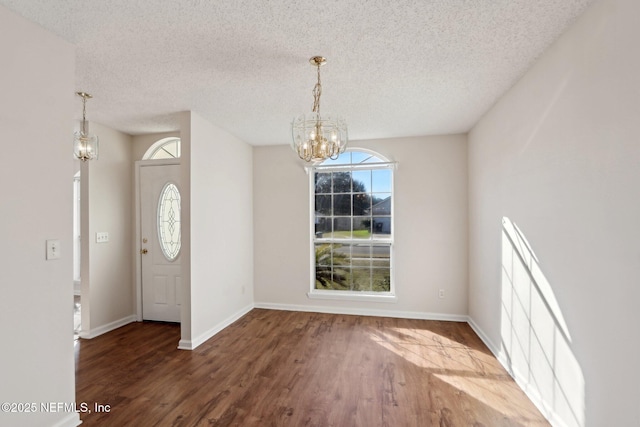 foyer with hardwood / wood-style flooring, a notable chandelier, a textured ceiling, and a wealth of natural light