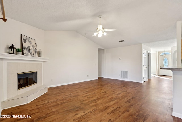 unfurnished living room with lofted ceiling, a tile fireplace, ceiling fan, and dark hardwood / wood-style floors