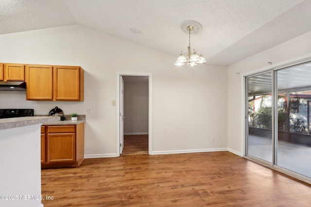 kitchen featuring pendant lighting, a notable chandelier, vaulted ceiling, and light hardwood / wood-style flooring