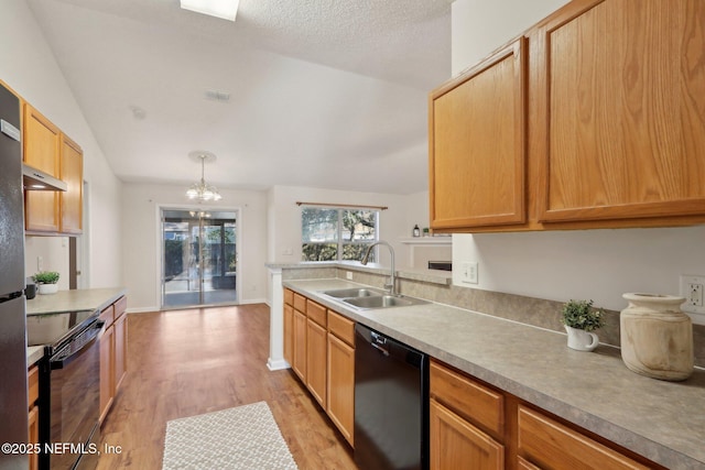 kitchen featuring pendant lighting, lofted ceiling, an inviting chandelier, black appliances, and sink