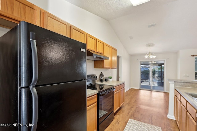 kitchen with lofted ceiling, black appliances, hanging light fixtures, a notable chandelier, and light hardwood / wood-style floors