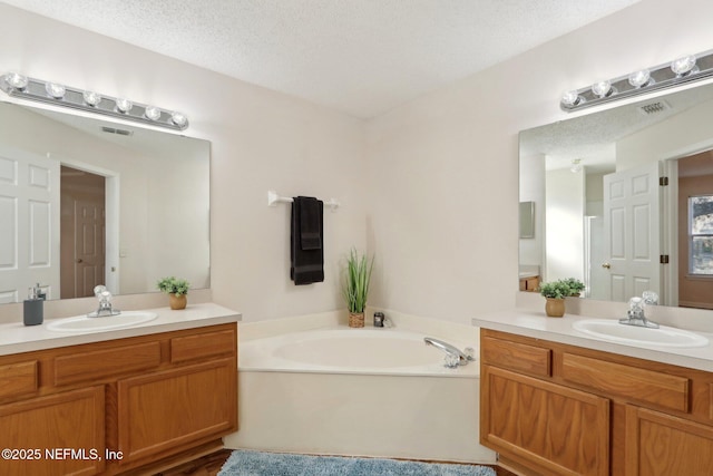 bathroom with vanity, a bath, and a textured ceiling