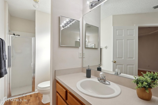 bathroom featuring walk in shower, vanity, a textured ceiling, hardwood / wood-style floors, and toilet