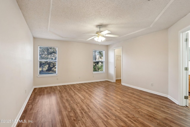 unfurnished room with ceiling fan, wood-type flooring, and a textured ceiling