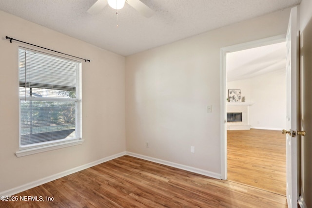 empty room with ceiling fan, wood-type flooring, and a textured ceiling