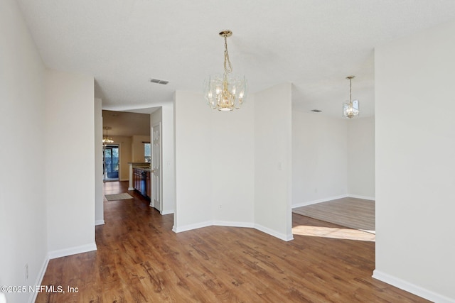 spare room with dark hardwood / wood-style flooring and a notable chandelier