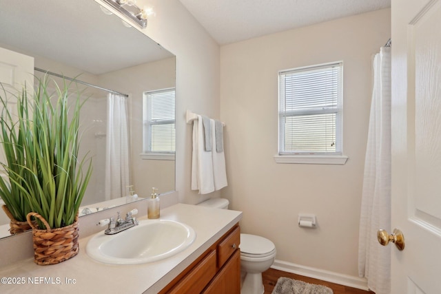 bathroom featuring plenty of natural light, toilet, and vanity