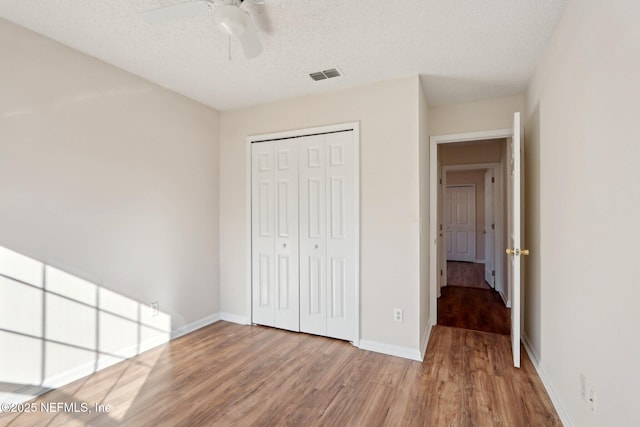 unfurnished bedroom with hardwood / wood-style floors, ceiling fan, a textured ceiling, and a closet