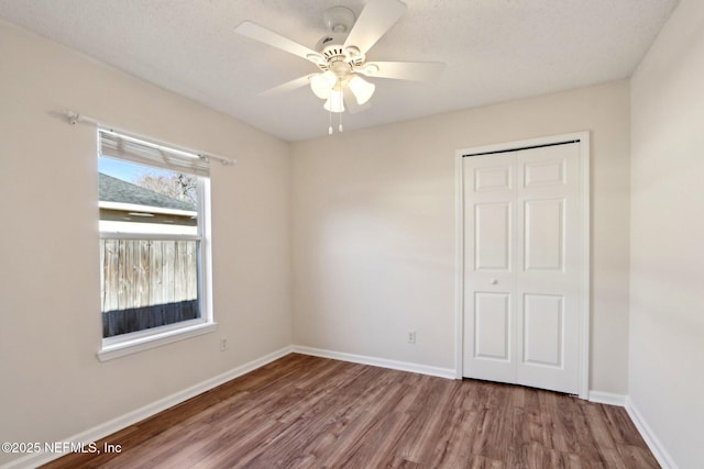 unfurnished bedroom with ceiling fan, a closet, and hardwood / wood-style floors