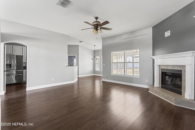 unfurnished living room featuring a textured ceiling, a tile fireplace, dark hardwood / wood-style floors, and ceiling fan with notable chandelier