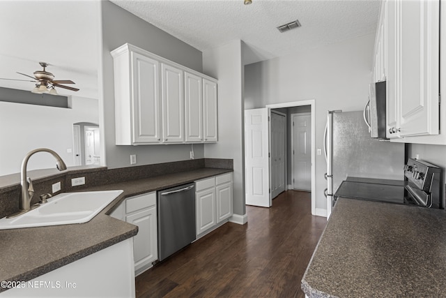 kitchen featuring a textured ceiling, stainless steel appliances, white cabinetry, and sink